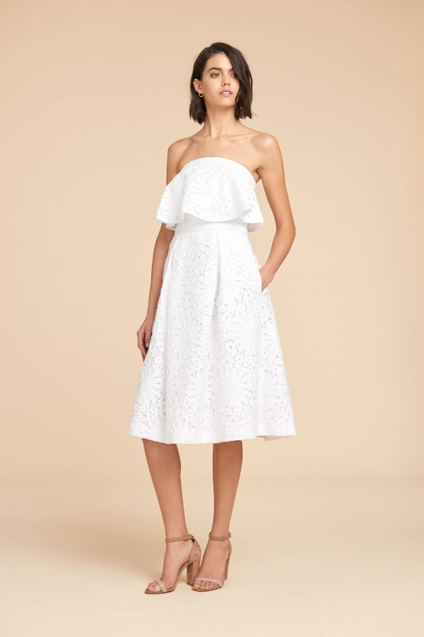a woman wearing a wedding dress with her hands in her pockets